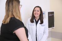 Physician in white coat talks to a patient in an exam room